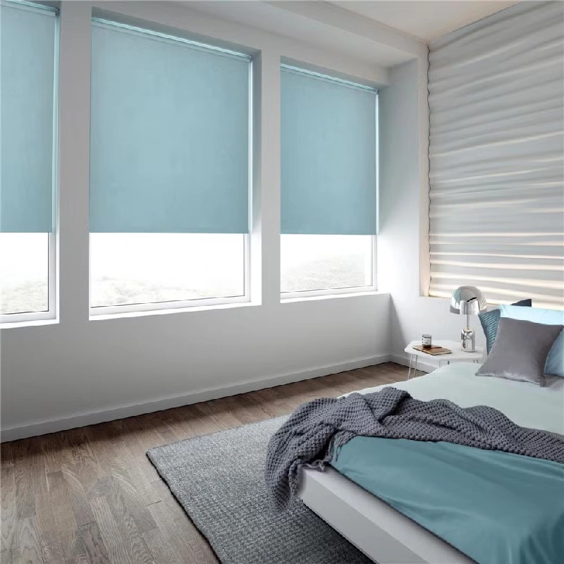 Dual light-blue roller blinds in a bright, modern bedroom.