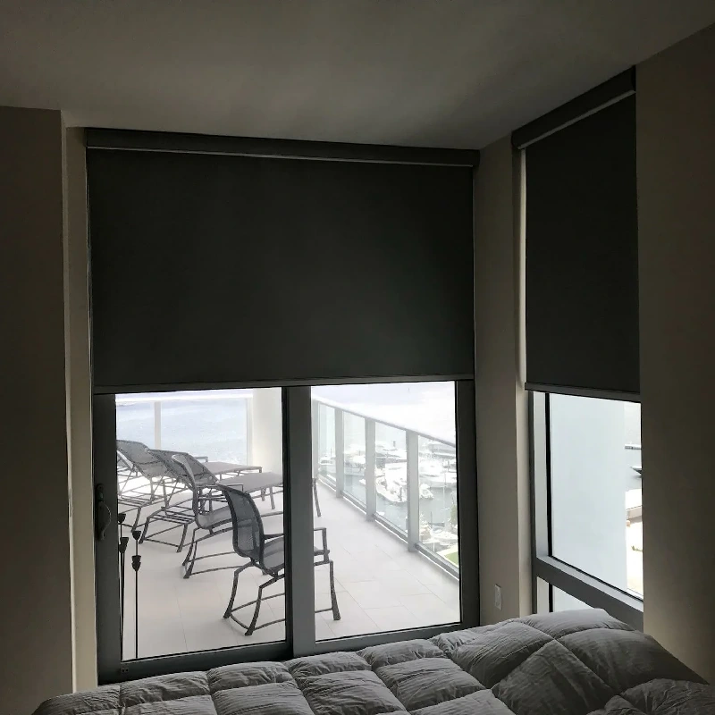 Sleek black blackout roller blinds on large balcony doors.