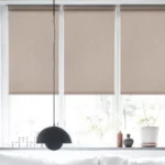 Three latte-colored blackout roller blinds installed side-by-side on a large window.
