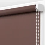 top roller of a chocolate brown blackout blind with a white control mechanism.