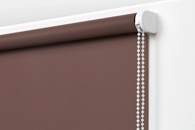 top roller of a chocolate brown blackout blind with a white control mechanism.